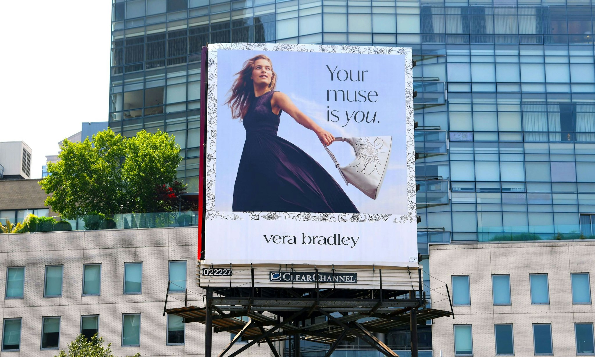 Billboard advertisement featuring a woman in a flowing black dress holding a bag, with the text 'Your muse is you.' and the 'vera bradley' logo displayed beneath.