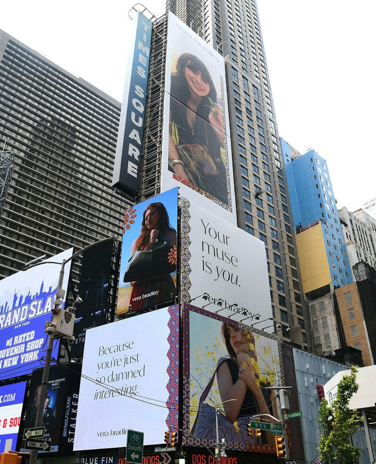 Multiple billboards in Times Square featuring Vera Bradley advertisements with the slogan 'Your muse is you.' and other messages, showcasing Zooey Deschanel and another model holding bags in various poses.